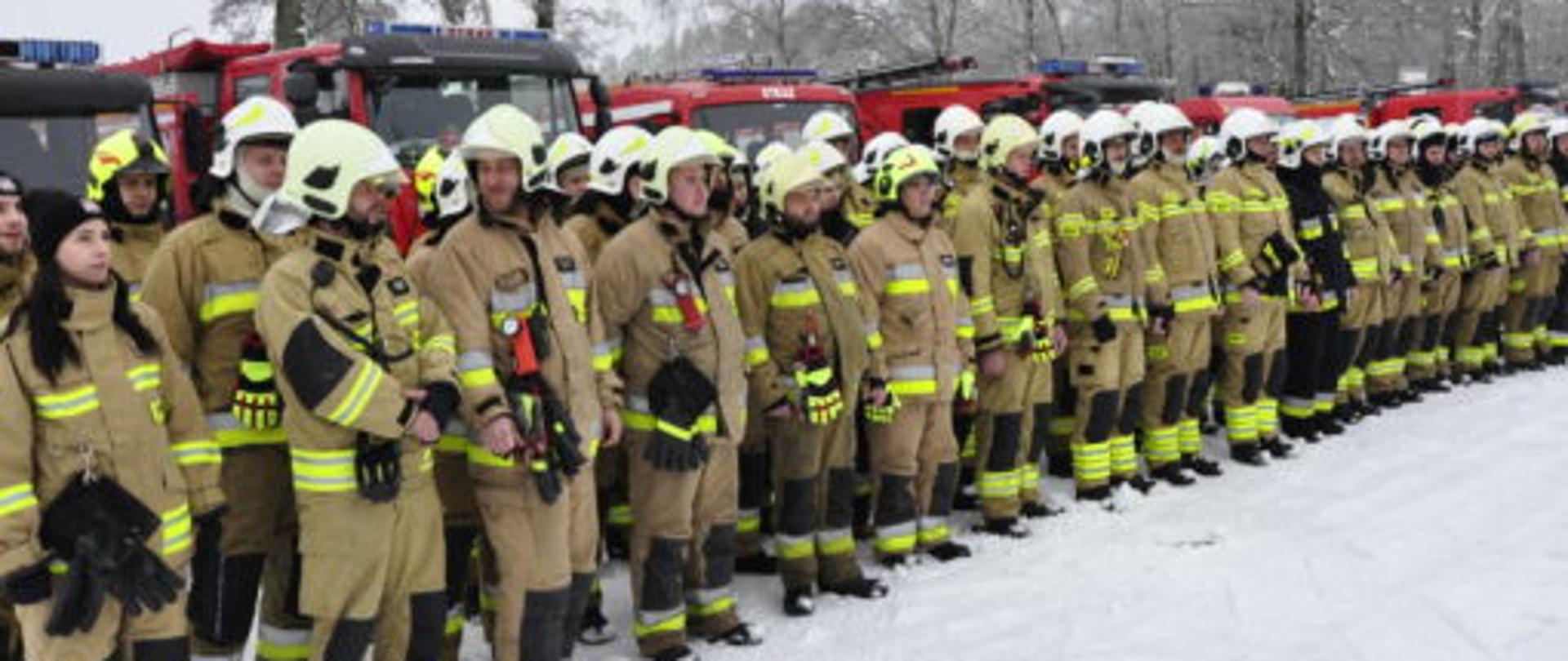 Uczestnicy manewrów ustawieni w dwuszeregu przed wozami bojowymi.