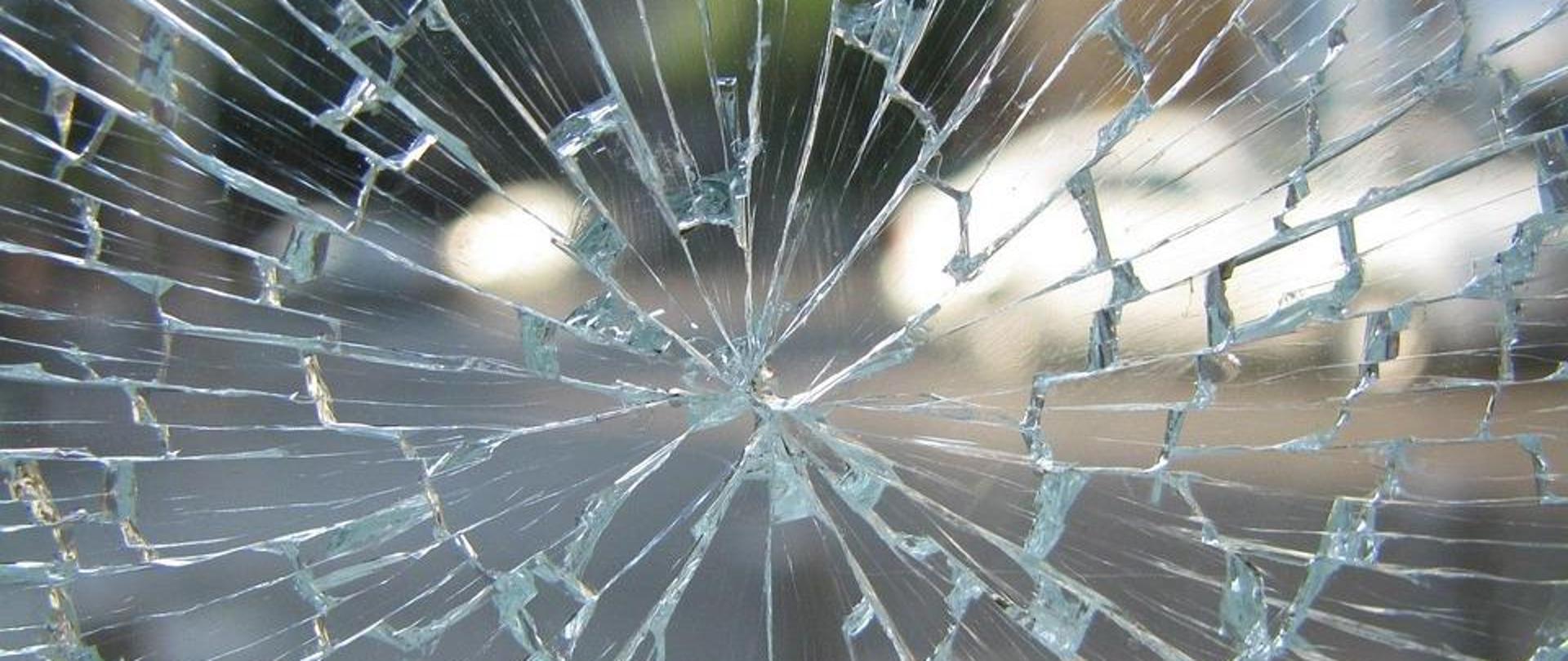 potłuczona szyba, za nią widoczny samochód