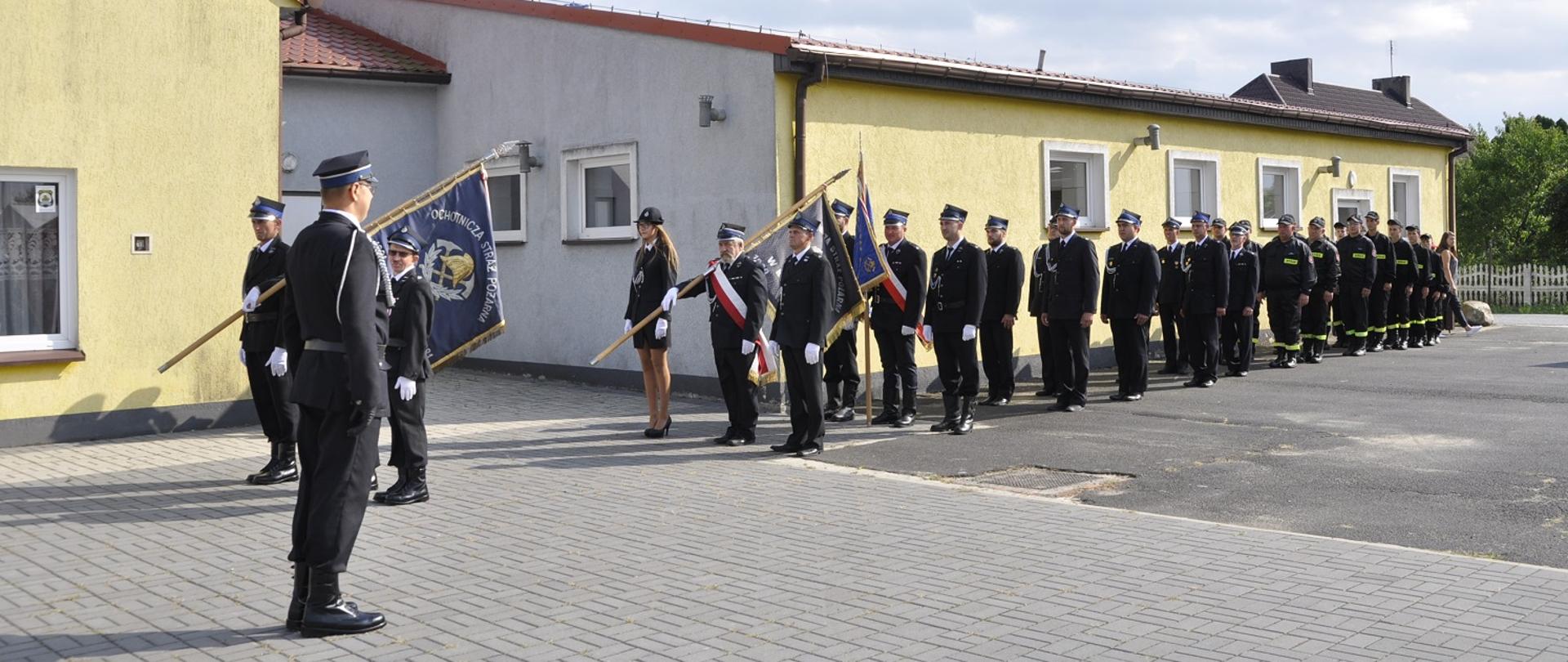 Na zdjęciu plac za strażnicą OSP Mchy dowolny∂ca wydaje komendę sztandarom i pododdziałowi