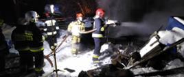 Strażacy PSP oraz OSP prowadzą prace dogaszające pogorzeliska budynku gospodarczego przy pomocy linii gaśniczej