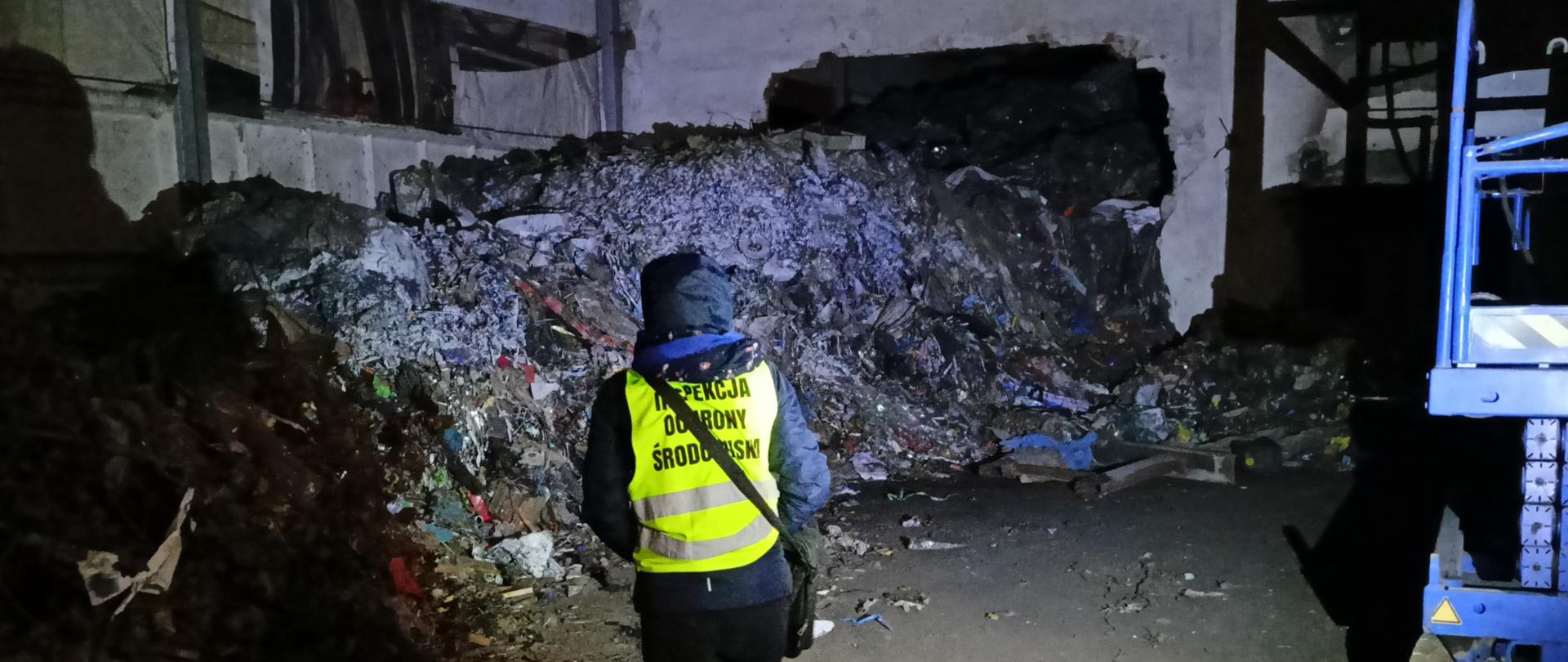 Inspektor WIOŚ w Gdańsku podczas oględzin hali wypełnionej odpadami