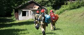 Strażacy PSP podczas ćwiczeń udają się do opuszczonego budynku na terenie kompleksu leśnego.