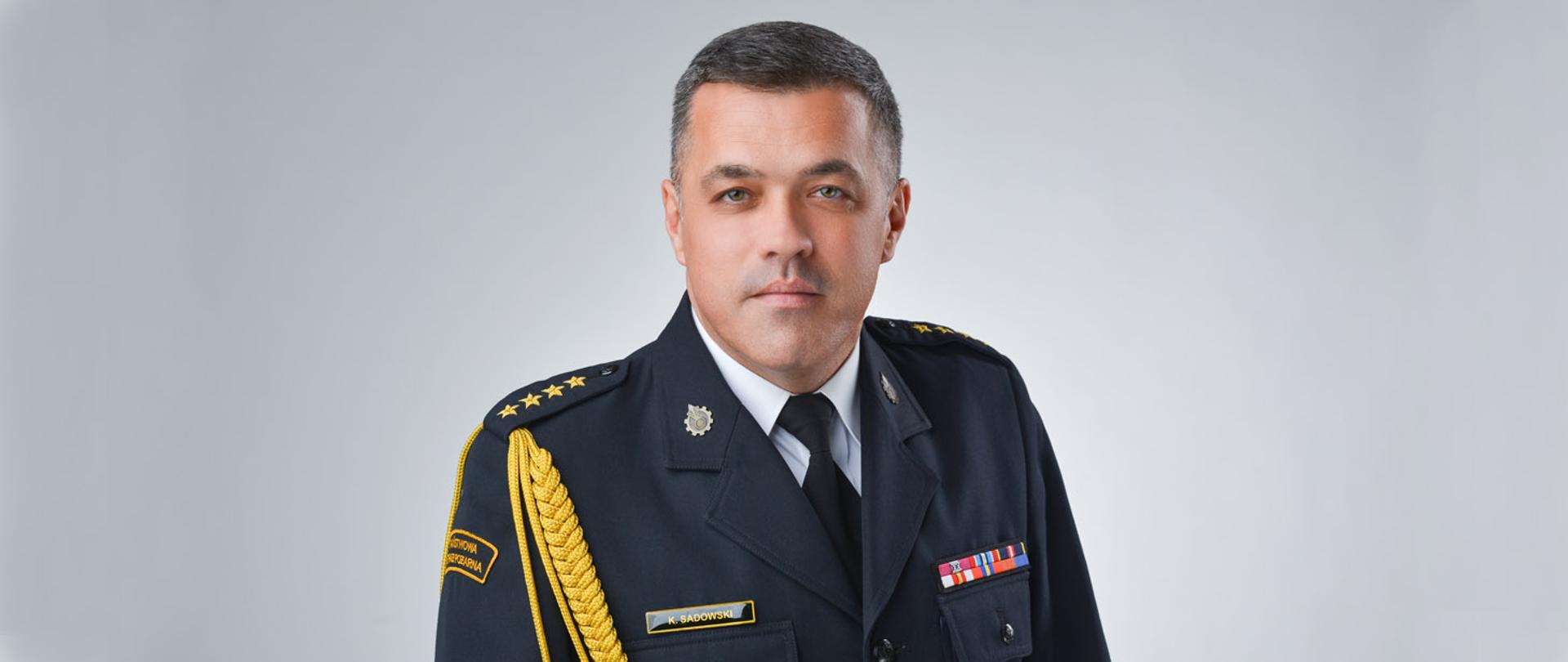 Na zdjęciu znajduje się Zastępca Komendanta Powiatowego PSP w Będzinie ubrany w mundur wyjściowy wraz ze sznurem.