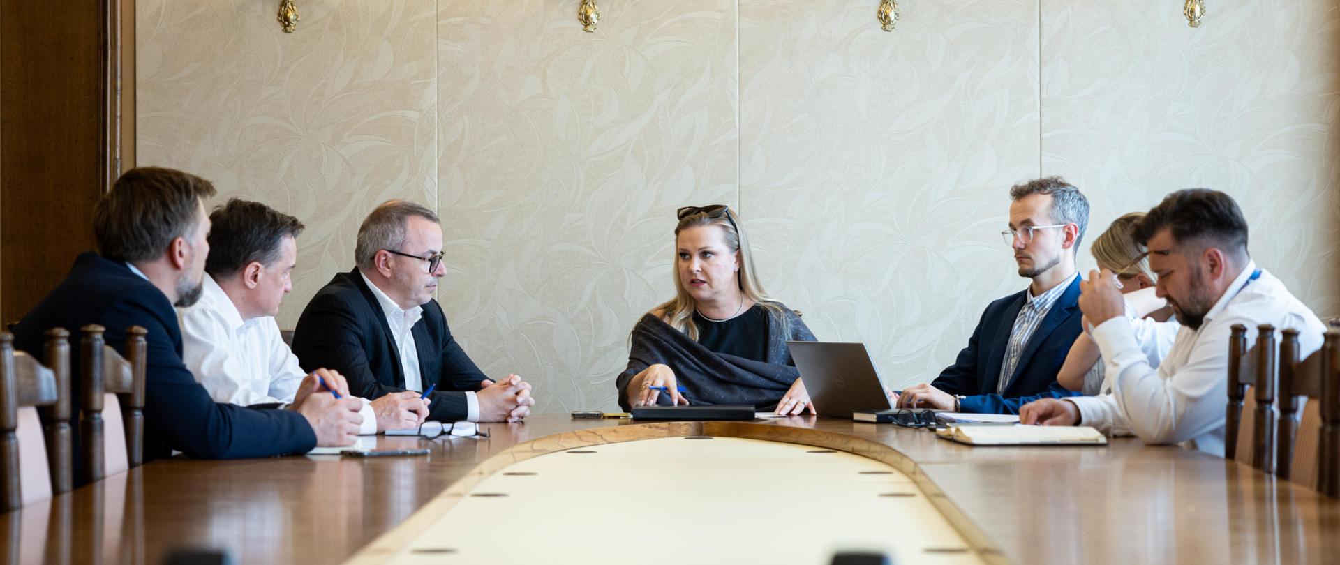 Na zdjęciu grupa osób, siedzących przy stole. 