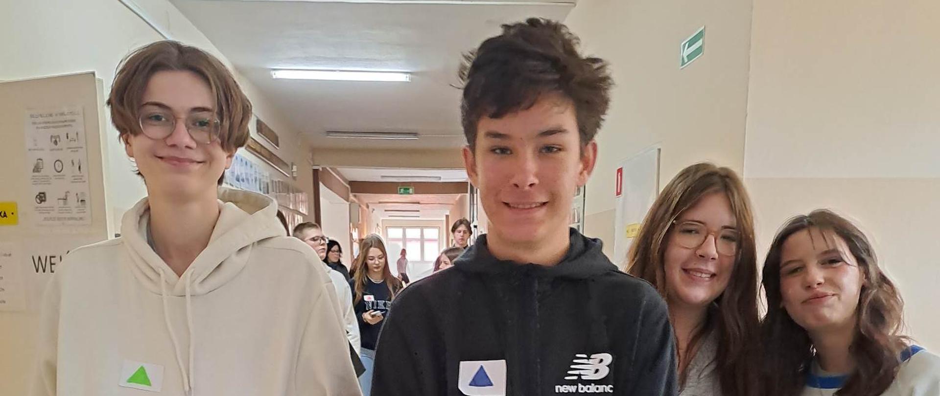 Zdjęcie uczniów na tle korytarza szkolnego.