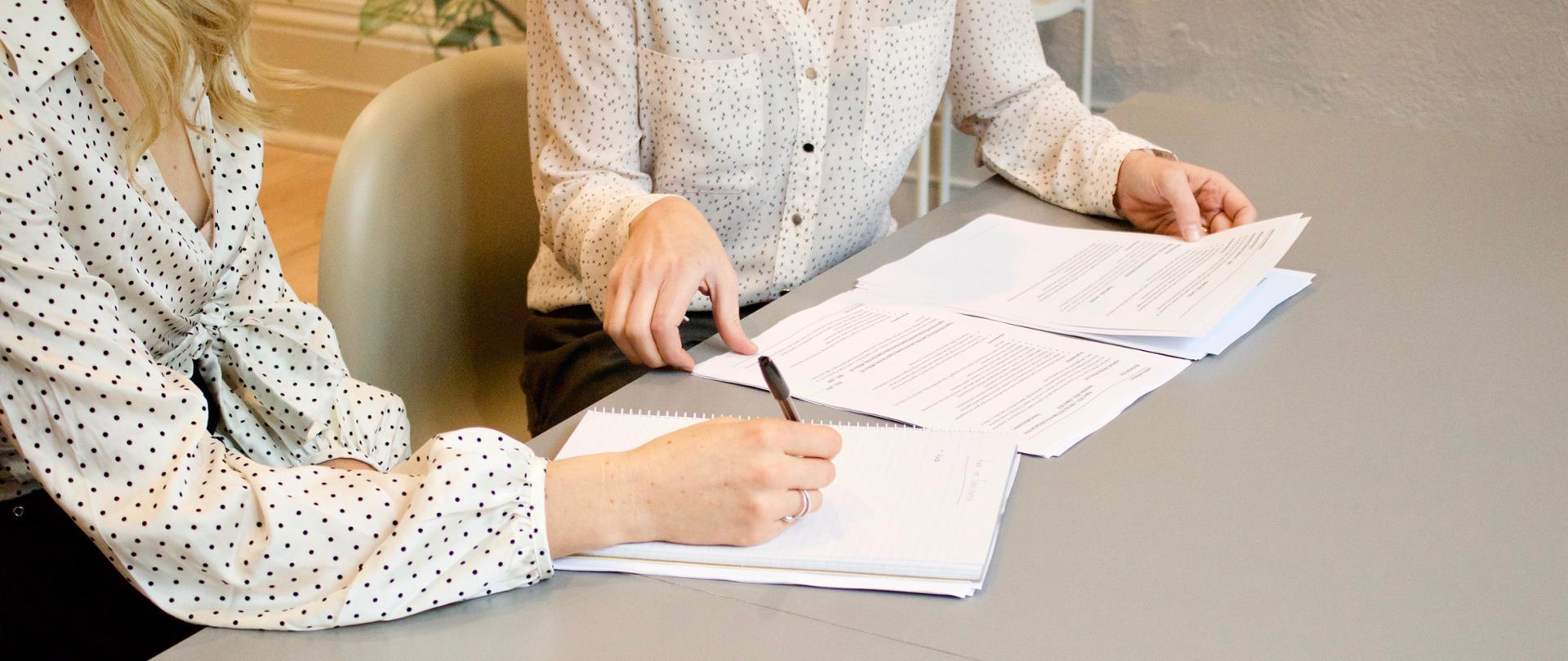 dwie kobiety siedzą przy stole na spotkaniu służbowym