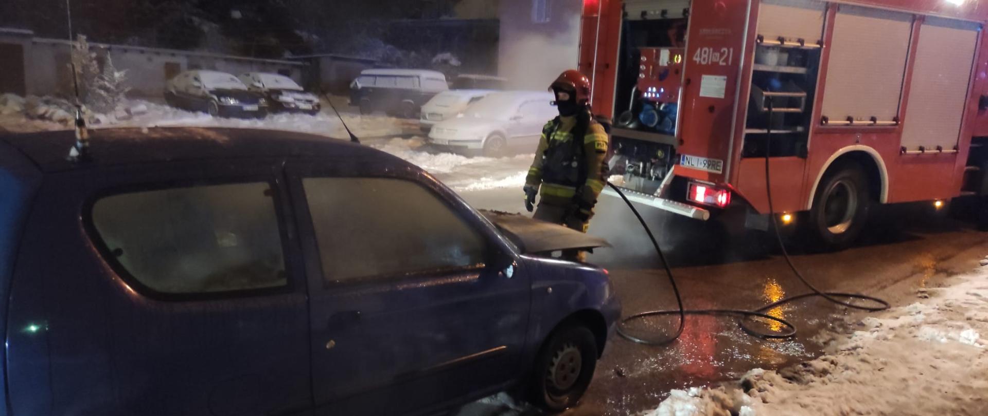 Zdjęcie przedstawia ugaszony pojazd oraz ratownika PSP 