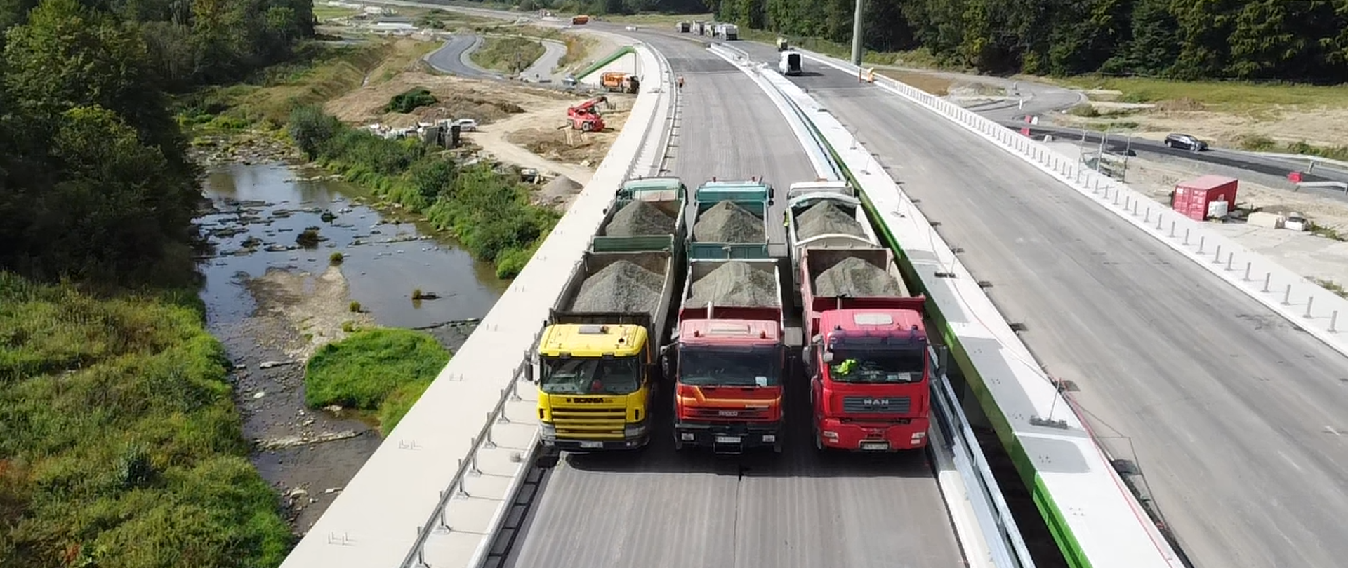 Widok z góry na estakadę, na której ustawione są załadowane samochody ciężarowe. Trwa próbne obciążenie obiektu.