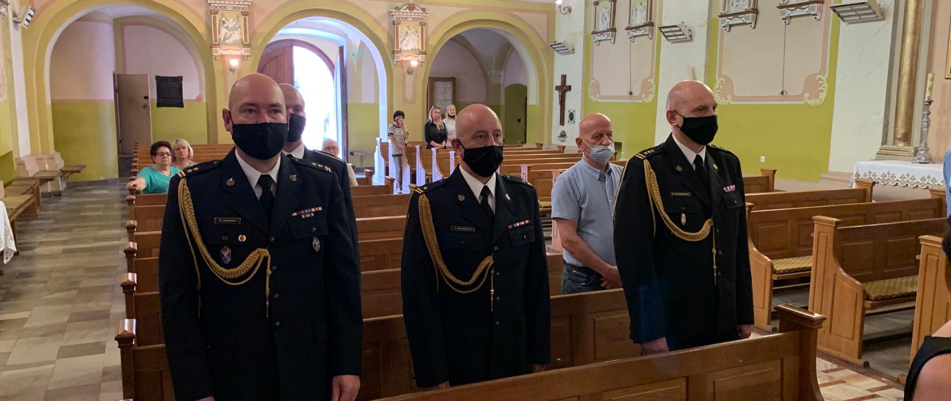 Pomieszczenia kościoła. Trwa msza święta poświęcona świętej pamięci byłemu komendantowi. Kierownictwo komendy powiatowej w Kutnie i jej pracownicy w mundurach wyjściowych w kolorze granatowym. Na ramieniu sznur galowy w kolorze złotym. Na tyłach kościoła inni cywilni uczestnicy mszy . 