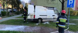 Strażacy pracujący przy dogaszaniu spalonego busa dostawczego przy ulicy Konarskiego.