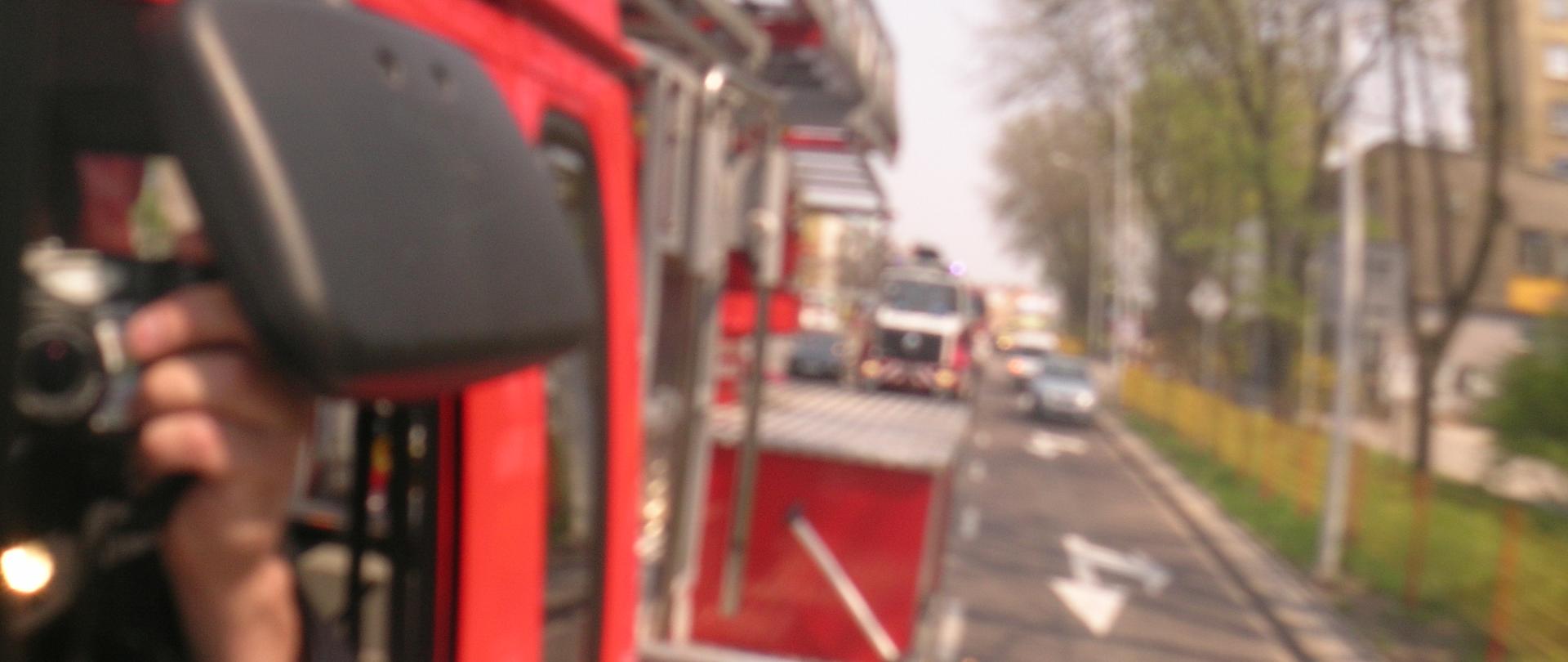 Historyczne zdjęcie przedstawiające przejazd ulicami miasta kolumny pojazdów pożarniczych z okazji Dnia Strażaka