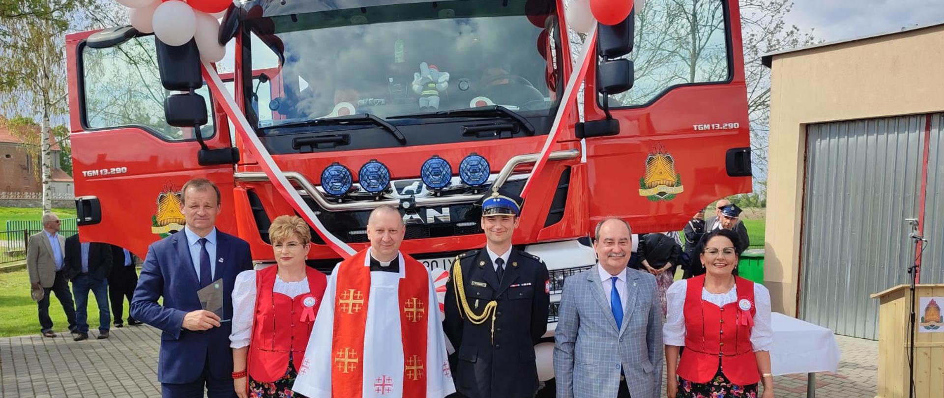 Zdjęcie zaproszonych gości na tle przekazywanego samochodu pożarniczego
