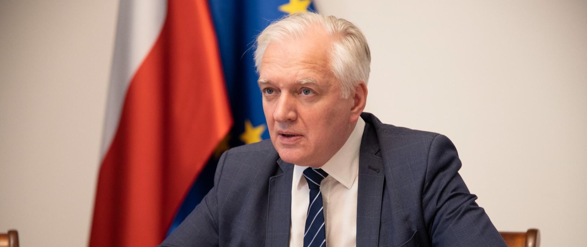 Wicepremier Jarosław Gowin siedzi przy stole i rozmawia online z amerykańską sekretarz handlu Giną Raimondo.