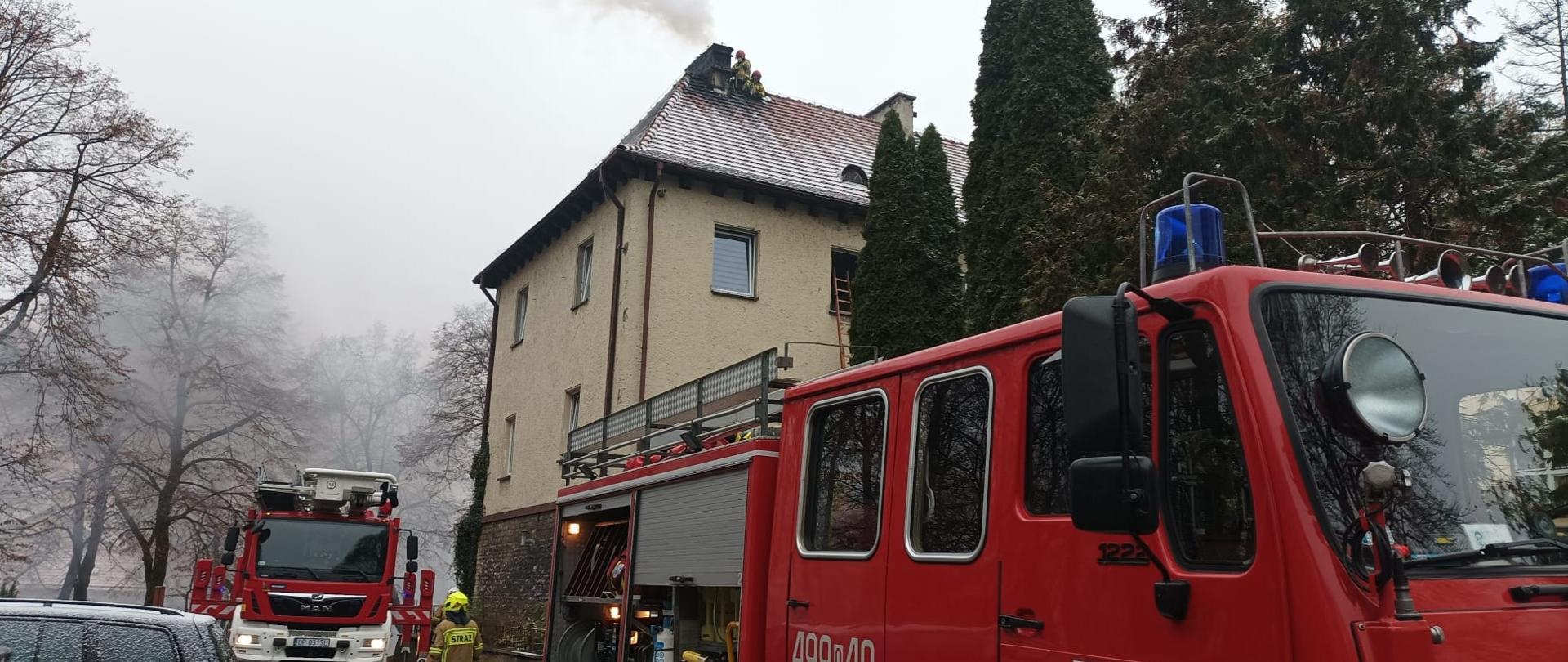 Na zdjęciu znajduje się budynek oraz pojazdy pożarnicze