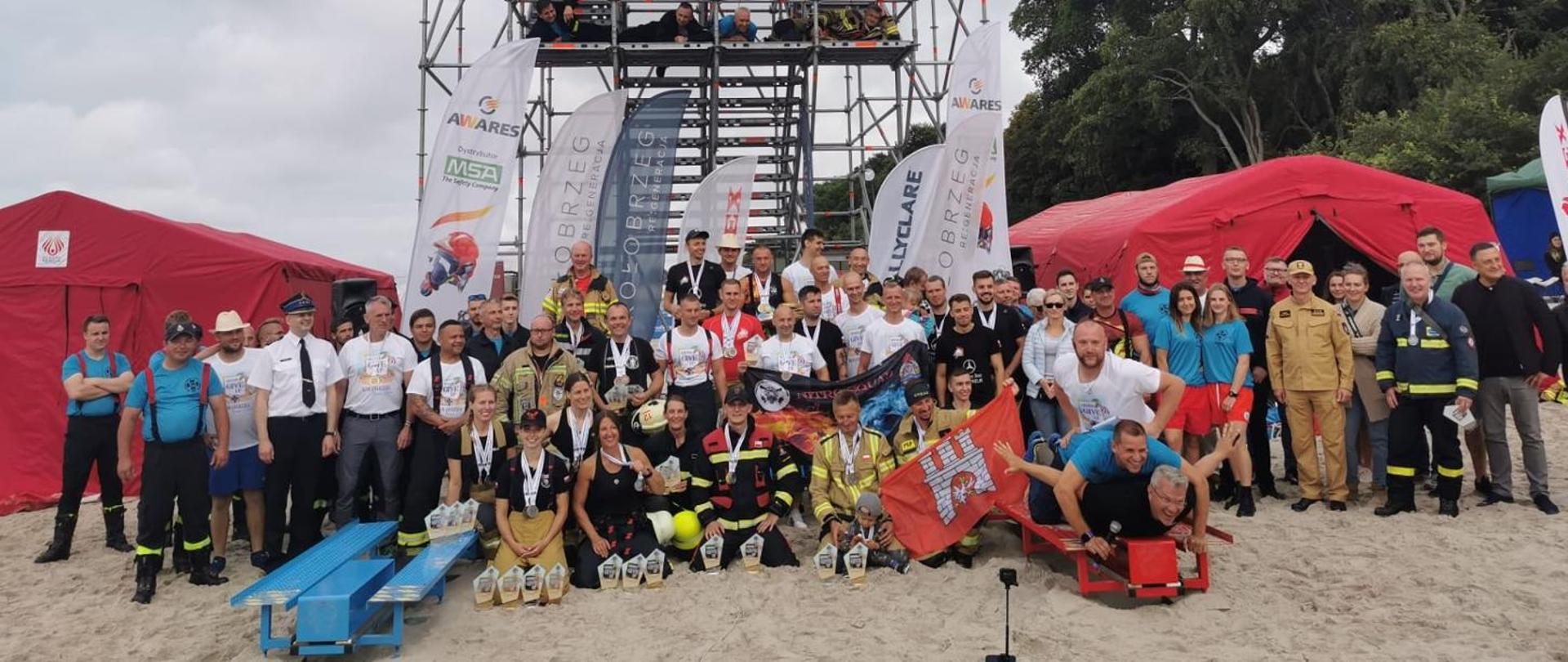 Zgjęcie grupowe zawodników i organizatorów na zakończenie zawodów na tle wiezy.