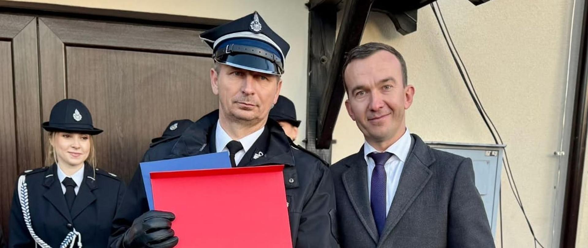 Zdjęcie przedstawia dwóch mężczyzn z pamiątkowym prezentem