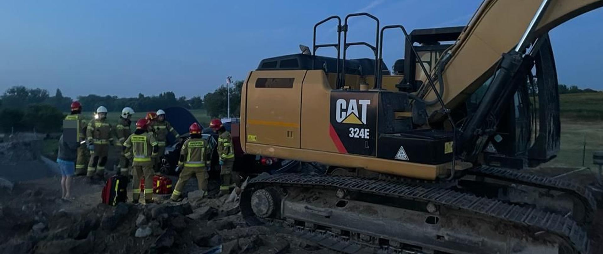 strażacy stoją koła koparki 