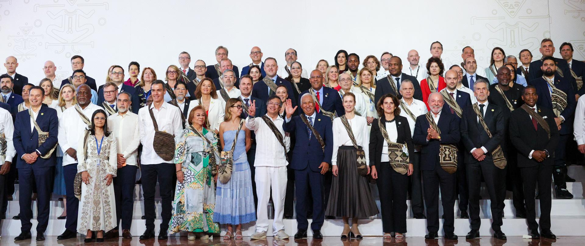 Group photo of participants at the EU-CELAC summit. Four rows of people standing formally, posing for the photo. Most of the men are wearing suits, while the women are wearing colourful dresses.