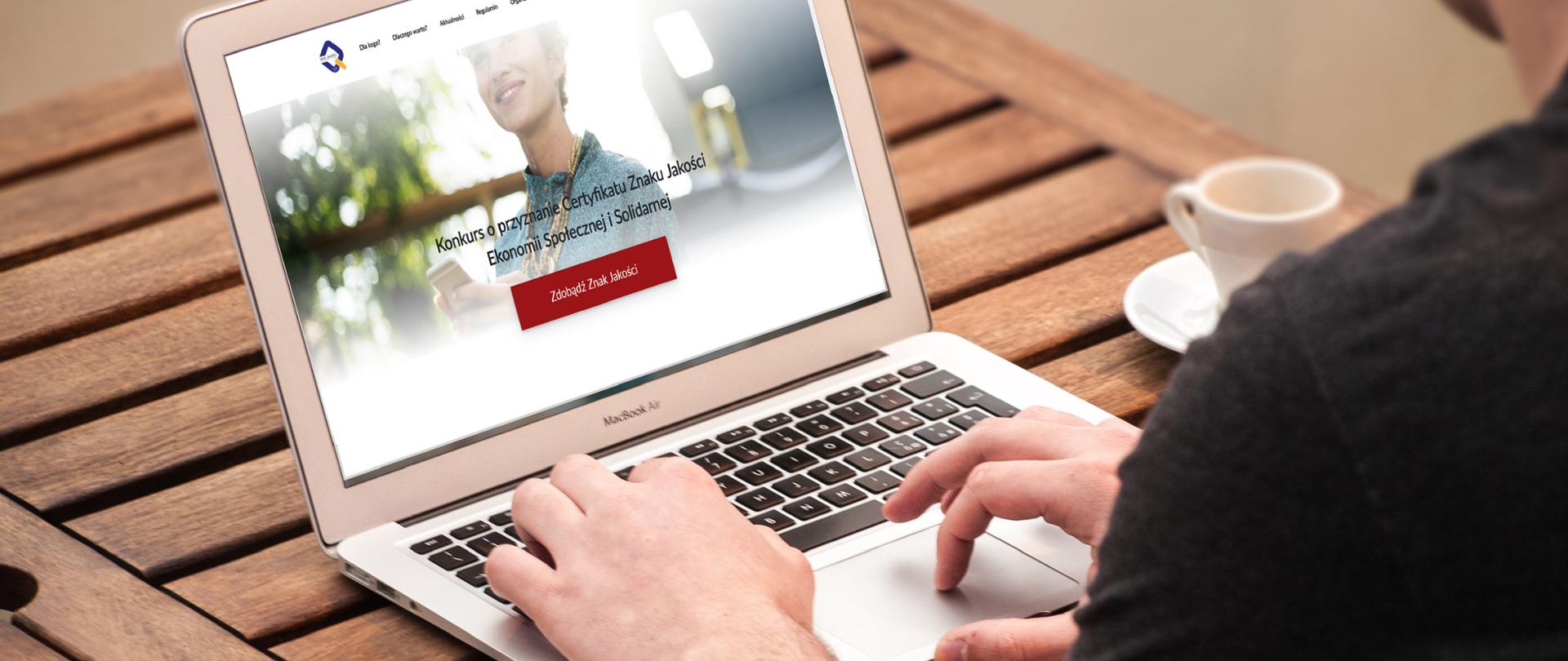 Laptop z napisem na ekranie "Konkurs o przyznanie Certyfikatu Znaku Jakości Ekonomii Społecznej i Solidarnej".