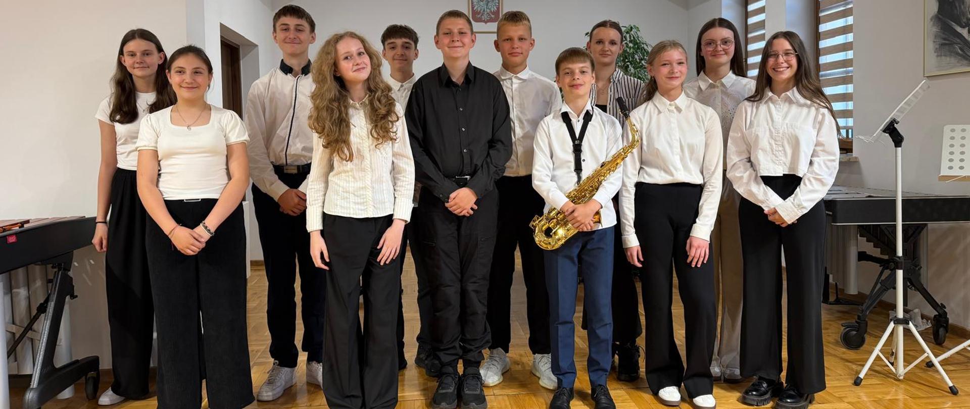 zdjęcie zbiorowe uczniów klas kończących, jeden uczeń trzyma w rękach saksofon