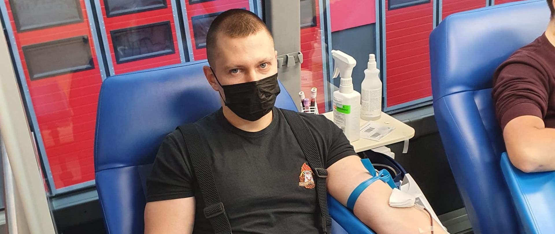 Zdjęcie przedstawia funkcjonariusza KP PSP w Lidzbarku Warmińskim oddającego krew w mobilnym punkcie RCKiK Olsztyn