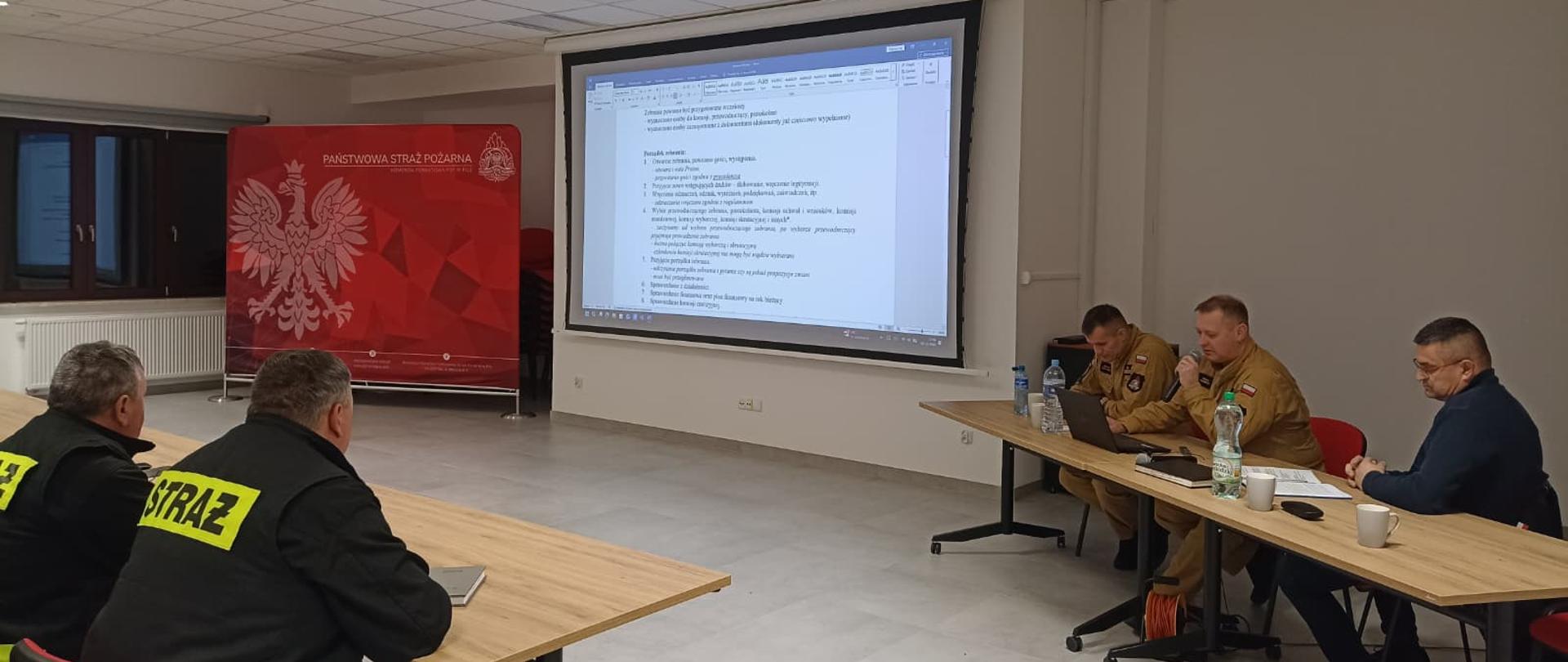 Prowadzący spotkanie omawiają przebieg zebrania w OSP