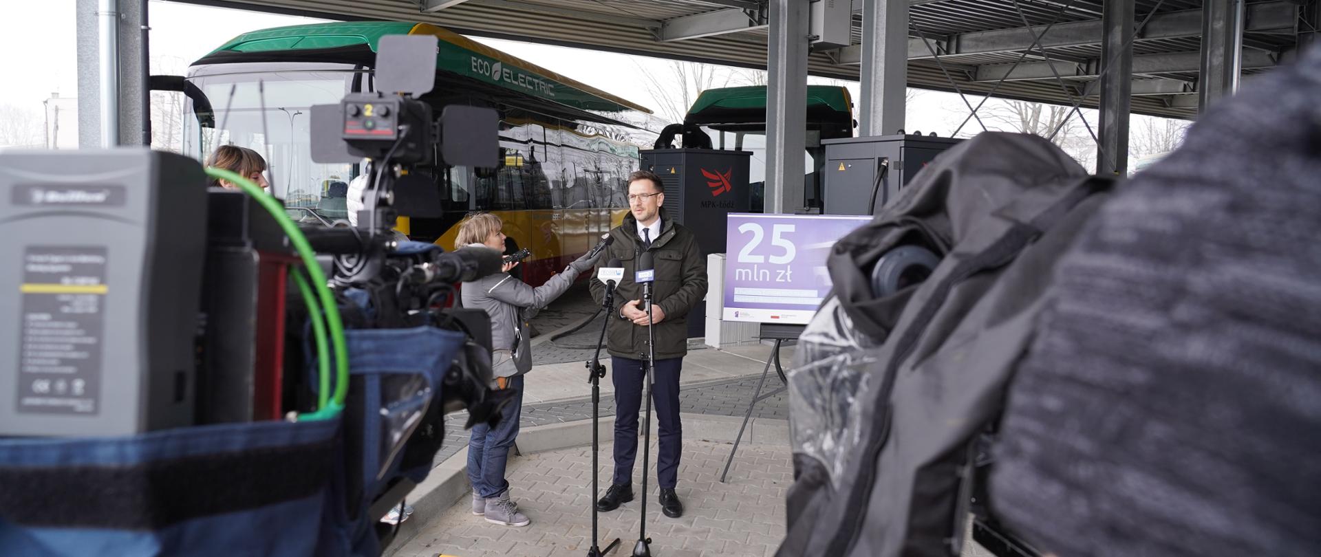 Wiceminister Waldemar Buda w zajezdni autobusowej mówi do dziennikarzy