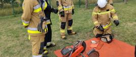 Zdjęcie przedstawia strażaka OSP, który zmienia łańcuch w pilarce spalinowej do drewna