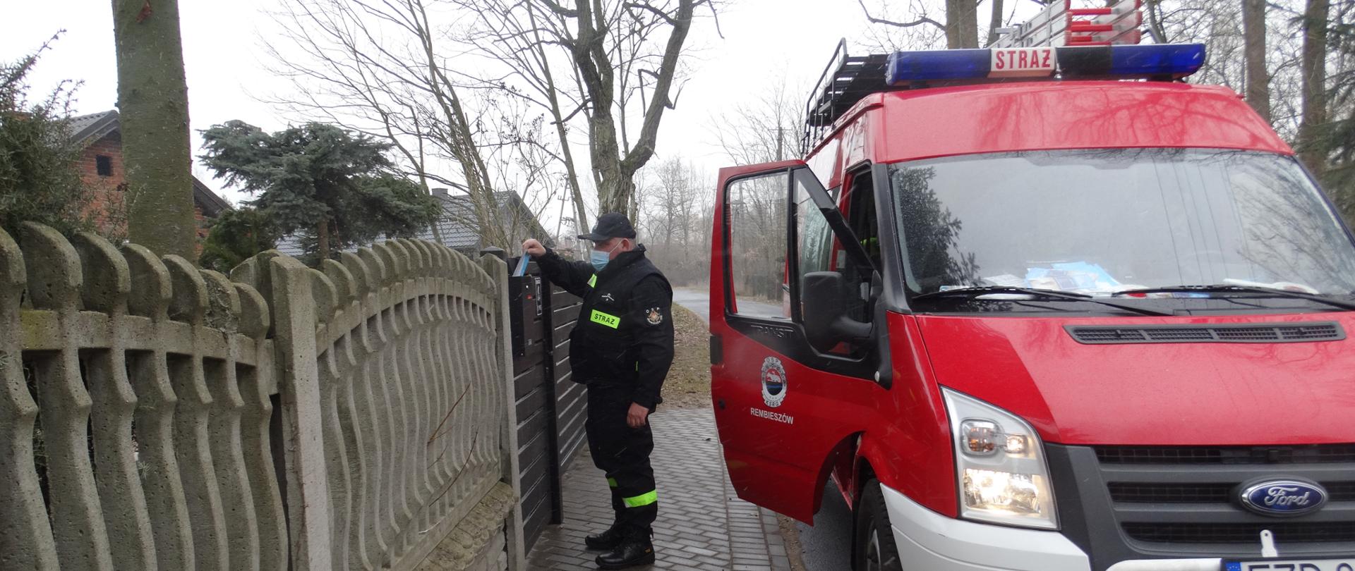 Zdjęcie przedstawia strażaka ochotniczej straży pożarnej roznoszącego ulotki po terenie swojej gminy.