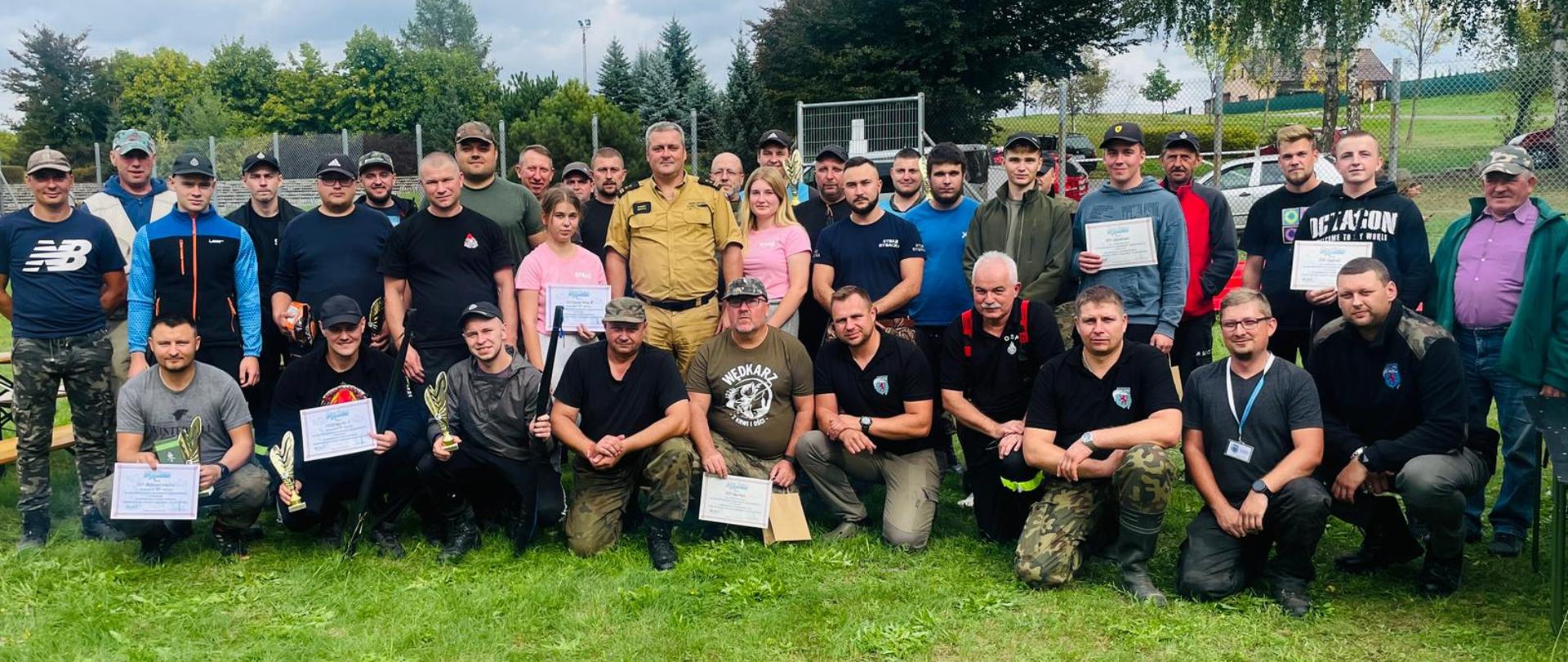 Uczestnicy zawodów wraz z organizatorami pozują do zdjęcia.