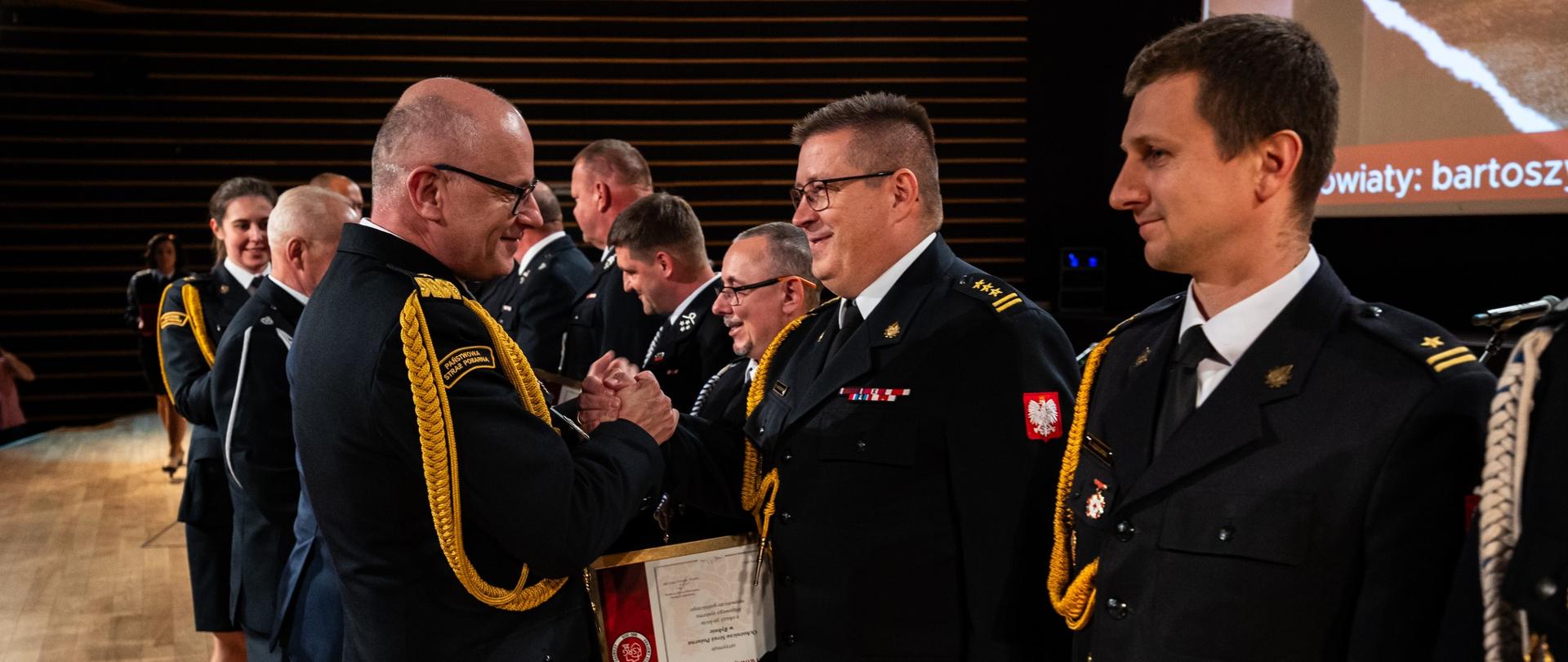 nadbrygadier Paweł Frysztak wręcza strażakom dyplomy. 