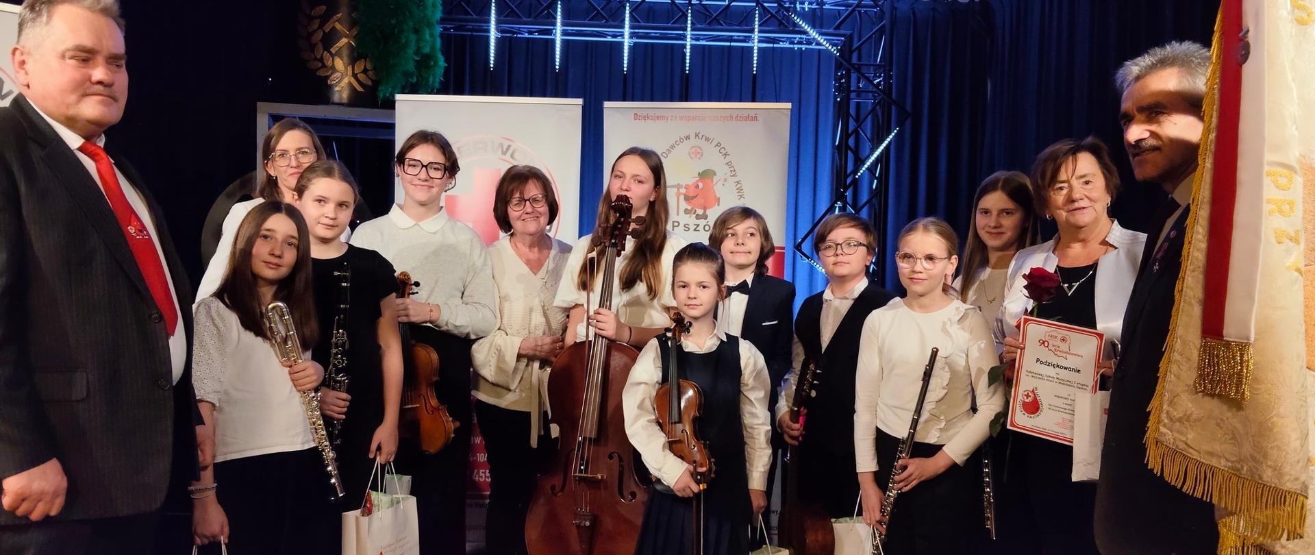 Grupa uczniów z instrumentami w rękach na scenie