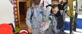 Targi edukacyjne. Sala sportowa w ZSZ w Rawiczu. Ze stoiska Komendy Powiatowej PSP w Rawiczu uczniowie zabierają ulotki wydane przez Szkołę Główną Służby Pożarniczej, dot. rekrutacji na uczelnię. 