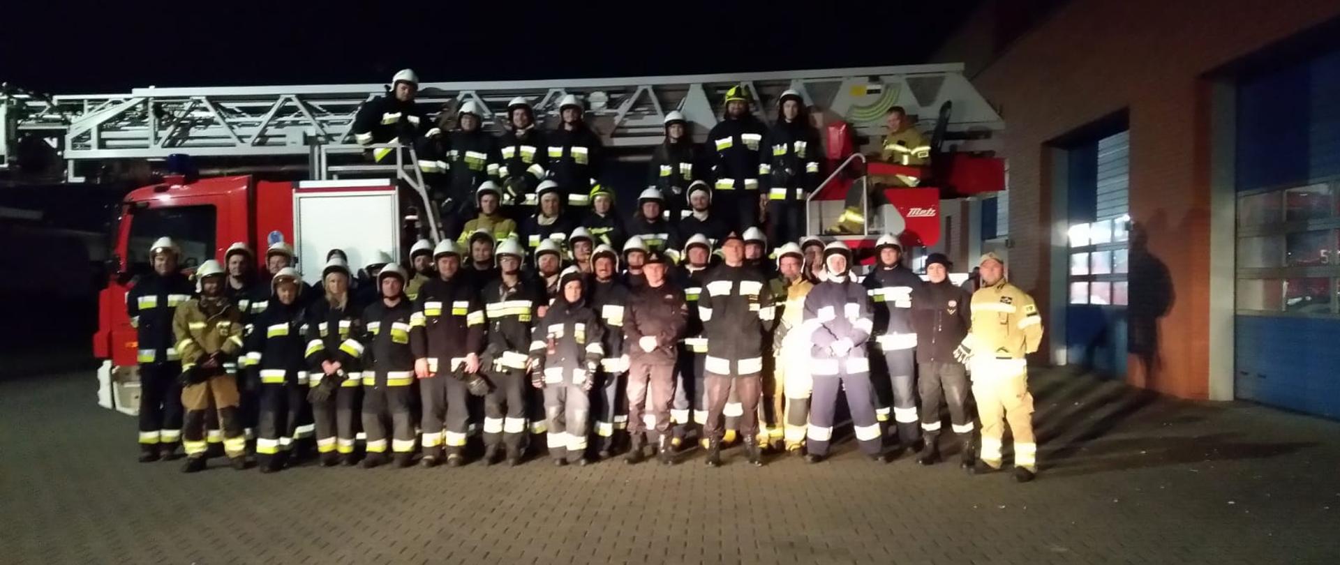 Grupa strażaków przy wozie strażackim