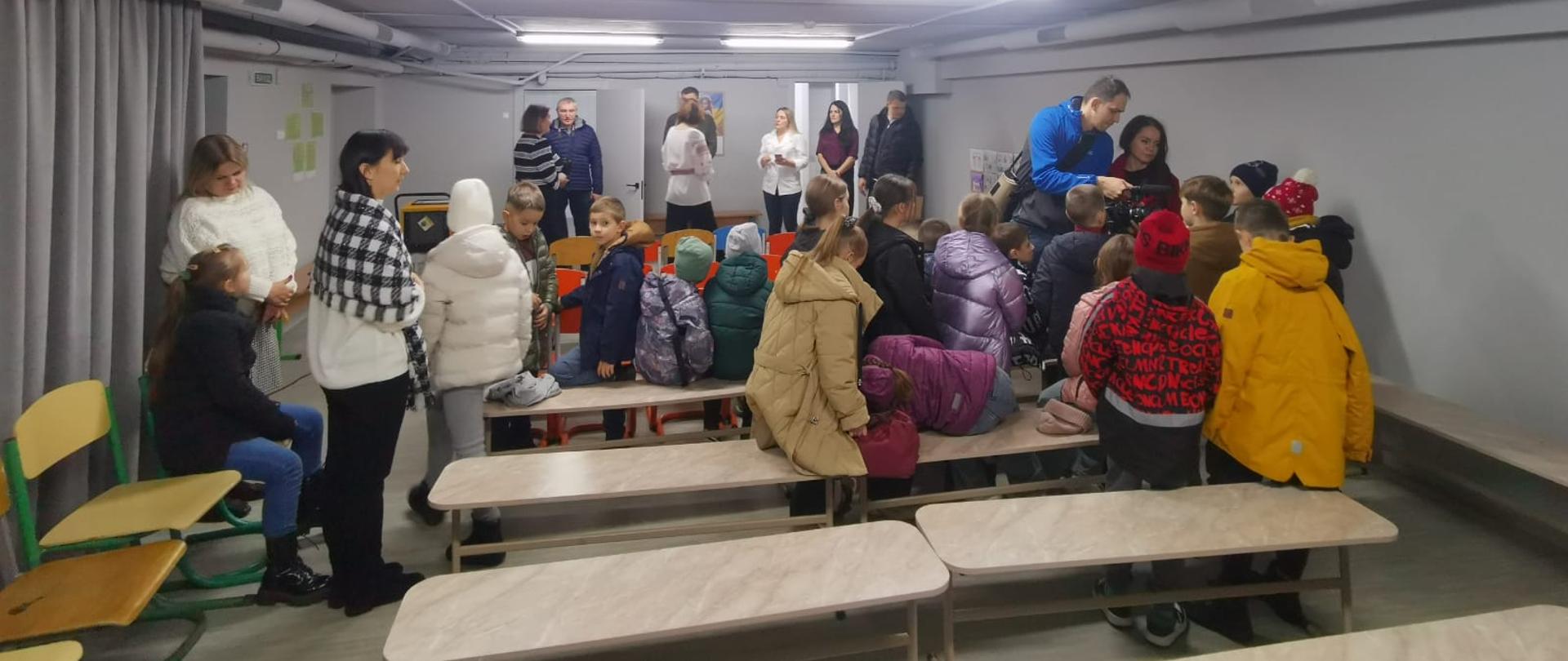 Grupa dorosłych i dzieci w schronie 