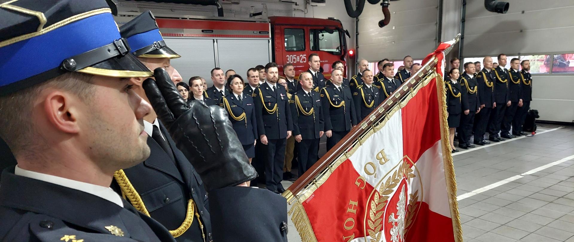 Zaproszeni goście stoją w szeregu na garażu JRG 5. Na pierwszym planie poczet sztandarowy KM PSP w Gdańsku.