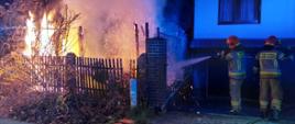 Strażacy gaszą pożar wiaty ogrodowej przy ulicy Kusocińskiego w Żarach. Płonienie sięgają dwóch metrów.