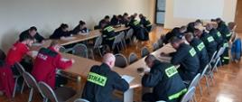 Na zdjęciu widać druhów OSP siedzących przy stołach w trakcie pisania egzaminu teoretycznego.
Zdjęcie wykonane na świetlicy Komendy Powiatowej PSP w Oleśnie.