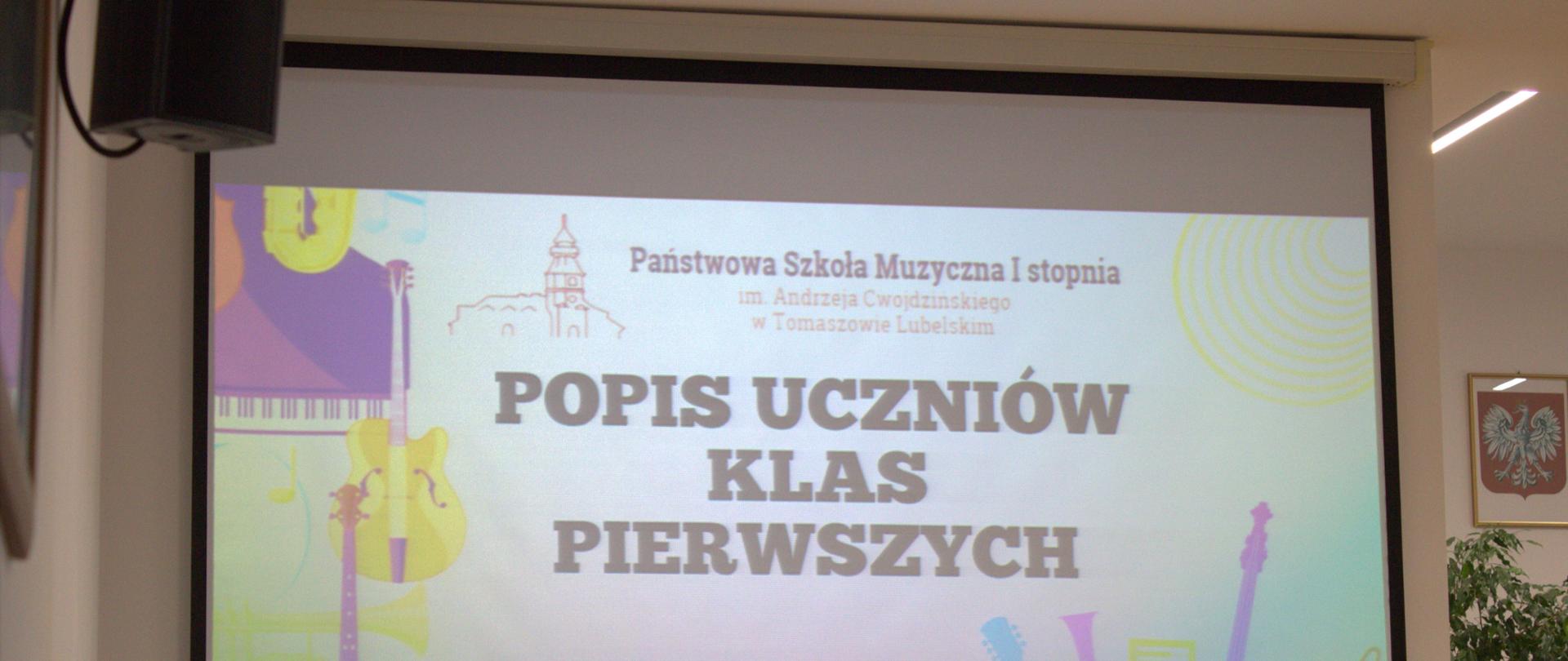 na zdjęciu projektor z bliska, na nim wyświetlony plakat, zawiera grafikę z kolorowymi instrumentami, logo szkoły oraz nazwę uroczystości z datą 