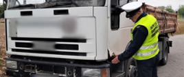 Inspektor wielkopolskiej Inspekcji Transportu Drogowego kontroluje stan techniczny ciężarówki przewożącej deski. Ze skorodowanej kabiny pojazdu wystawały ostre elementy.