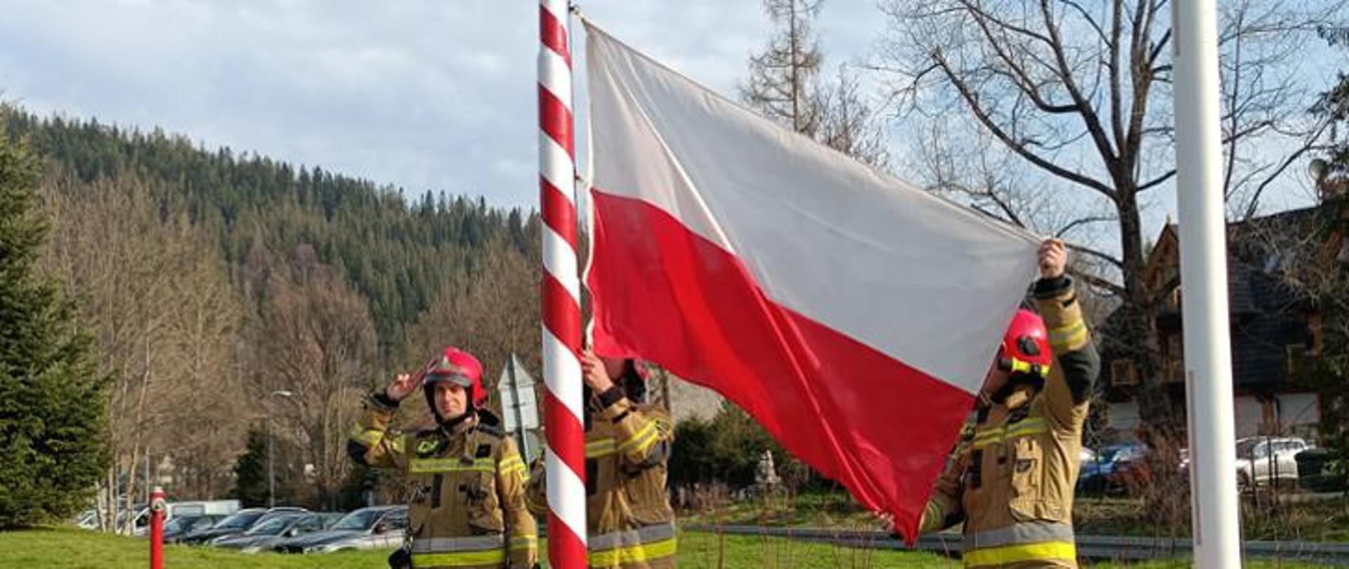 Strażacy uroczyście podnoszą flagę na maszt