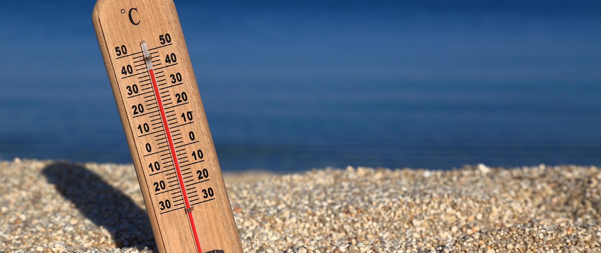 Termometr z wysoką temperaturą wbity w piasek na plaży.