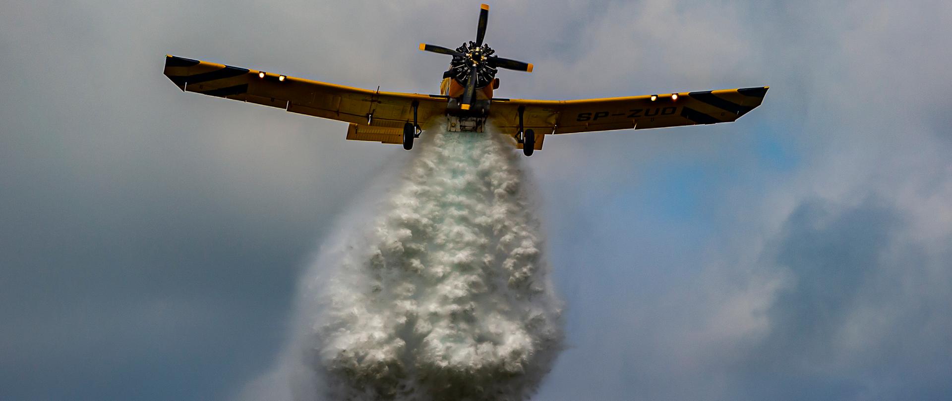 Samolot na niebie widziany od spodu podczas zrzucania wody