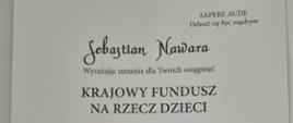 Dokument na białym tle informujący o tym, że e Sebastian Nawara z klasy gitary Pana Adriana Furmankiewicza został przyjęty do grona stypendystów Krajowego Funduszu na rzecz Dzieci w roku szkolnym 2023/24.
