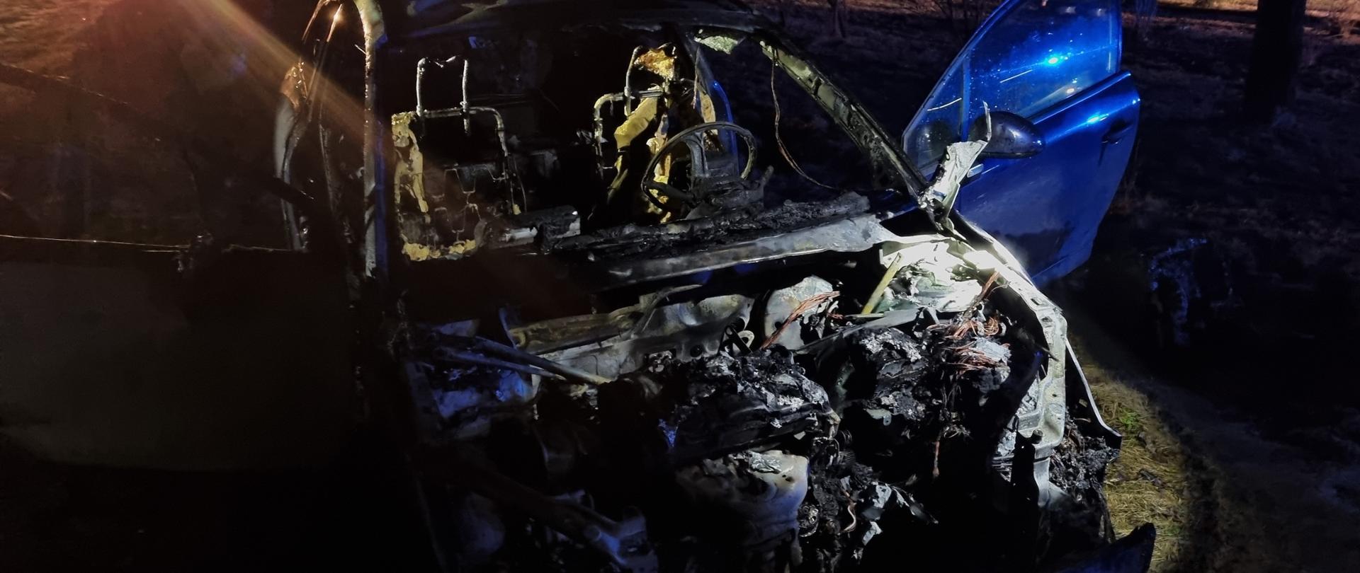 Zdjęcie przedstawia całkowicie spalony samochód osobowy. 