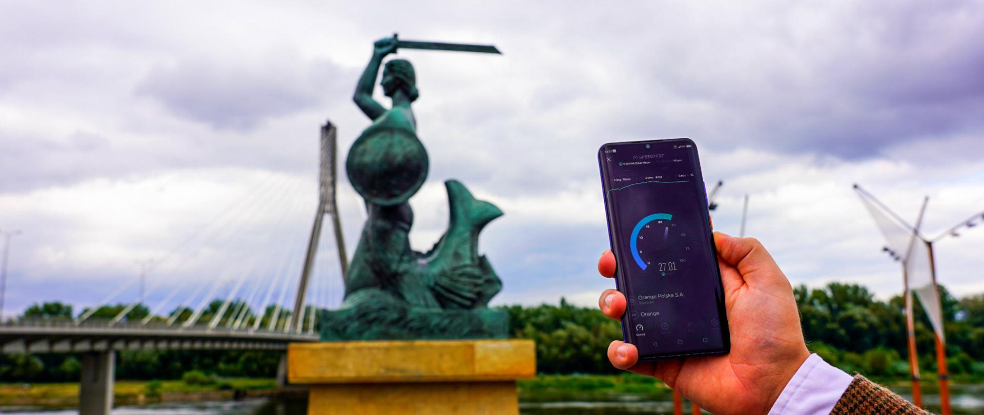 Telefon, a w tle pomnik Syrenki warszawskiej i Most świętokrzyski.