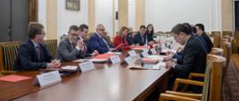 Przedstawiciele polskiej i chińskiej administracji skarbowej podczas spotkania, uczestnicy siedzą przy stole.