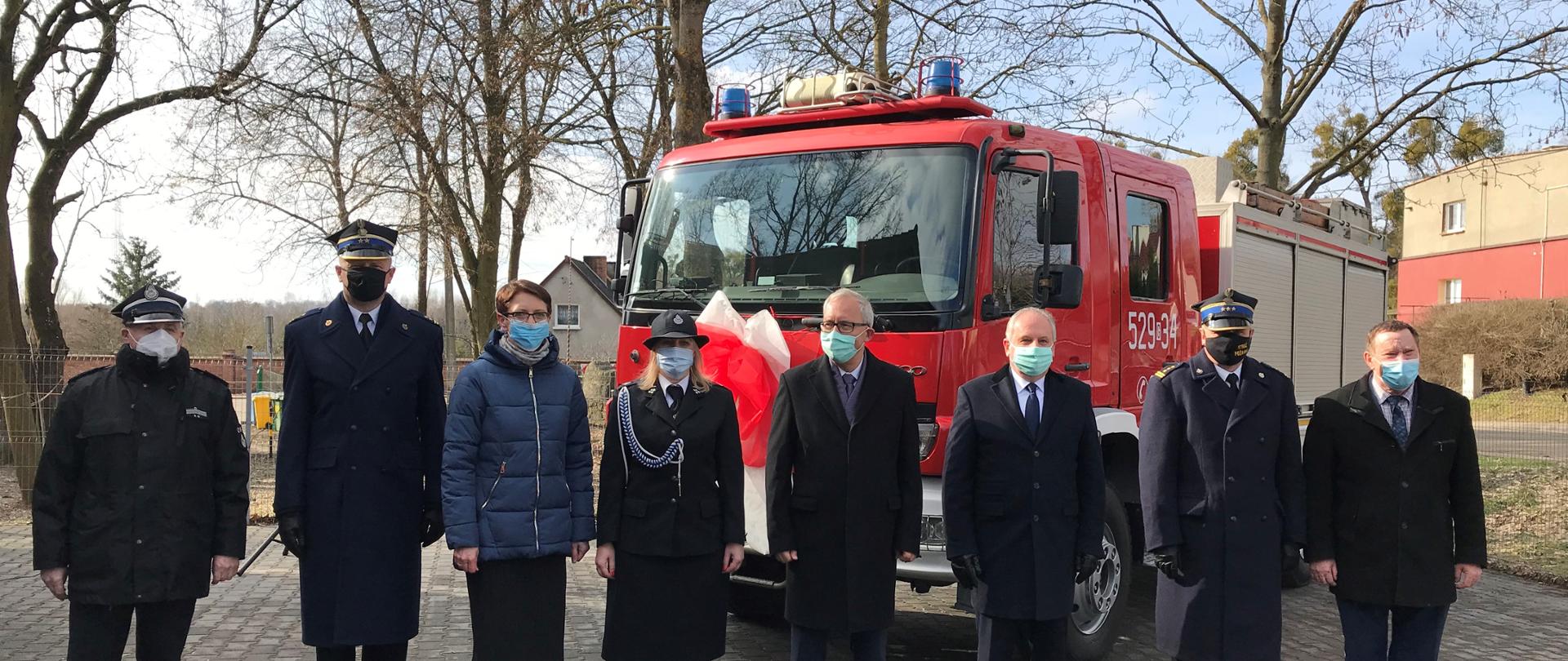 Zdjęcie przedstawia zaproszonych gości na tle samochodu gaśniczego.