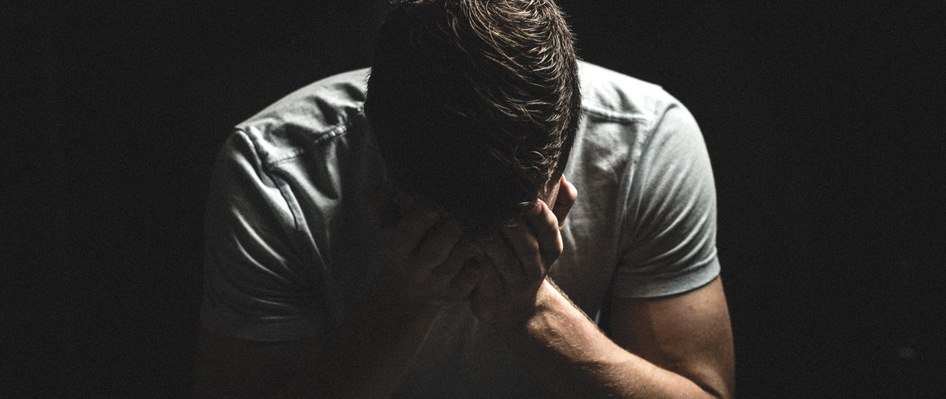 Mężczyzna ukrywający twarz w dłoniach