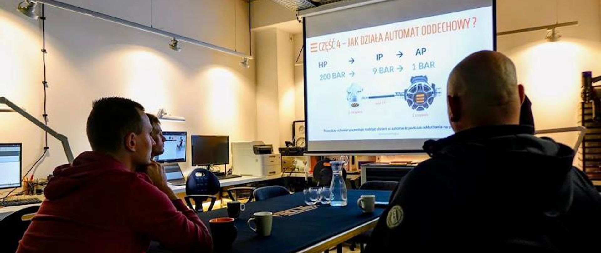 Zdjęcie z seminarium na którym widać jeden z slajdów szkoleniowych oraz uczestników.